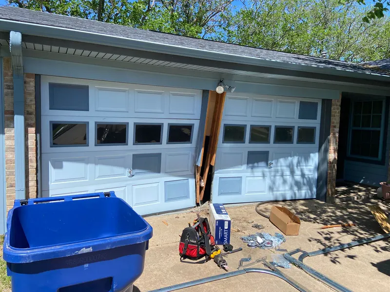 Garage door installation in progress with tools laid out on the driveway
