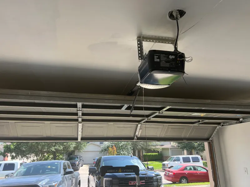 Garage door open from the inside showing the opener unit and rail after a repair